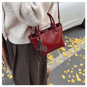 Détail du sac bandoulière rouge vin en cuir avec charme raquette de tennis dorée