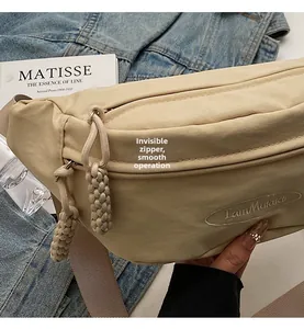 Close-up of smooth hidden zipper and woven puller on beige nylon crossbody fanny pack
