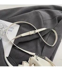 Detail of adjustable shoulder strap with silver buckle and clasp on cream bucket bag