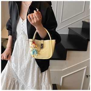 Detail of pale yellow patent leather mini bucket bag with silver twist lock and pearl strap