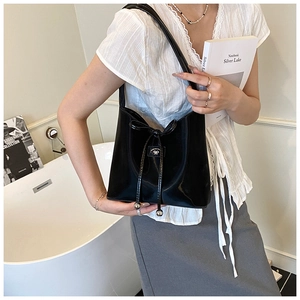 Détail du sac à bandoulière noir brillant avec cordon de serrage et boule métallique
