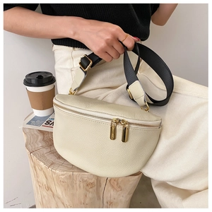 Detail of cream pebbled leather waist bag with gold zippers and canvas strap on a model