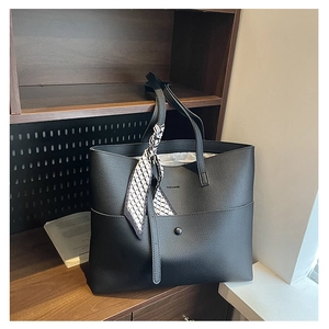 Close-up of black litchi leather tote bag with geometric scarf detail and snap pocket