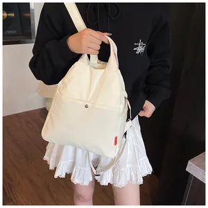 Detail of multi-functional cream nylon chest bag showing metal snap pocket and side label