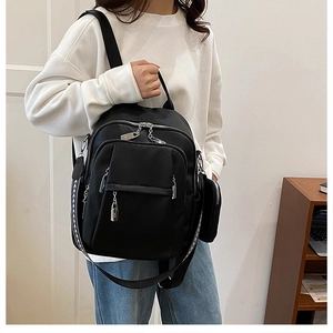 Detail of black pebbled leather backpack with woven straps and detachable side pouch