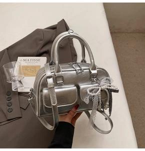 Detailed macro view of silver metallic Boston bag with magnetic pockets and pearl bow charm
