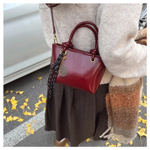 Détail du sac seau bordeaux avec pendentif raquette de tennis en décor d'automne