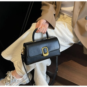 Détail du sac à main minimaliste en cuir noir avec boucle dorée et bandoulière réglable