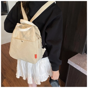 Rear view of model wearing a beige lightweight multi-functional backpack with red fashion tag