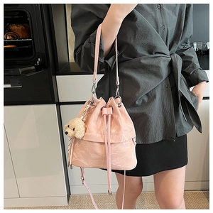 Pink patent leather drawstring bucket bag with cute poodle plush charm detail