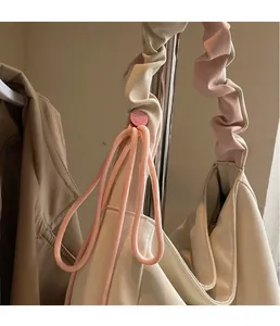 Detail of off-white tote bag with pink smile buckle and ruched handle on a hanger