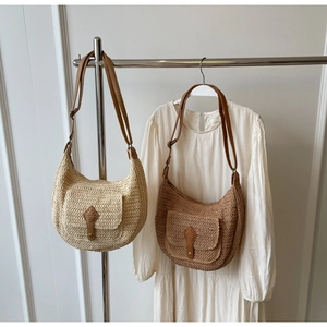 Detailed close-up of straw semi-circle bags with premium leather straps and textured weaving