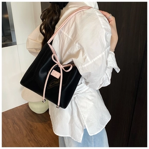 Détail du cabas en cuir verni noir avec passepoil rose et nœud délicat de décoration