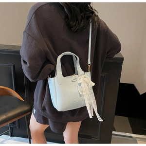 Detail of light blue crossbody bucket bag with litchi texture and elegant lace ribbons