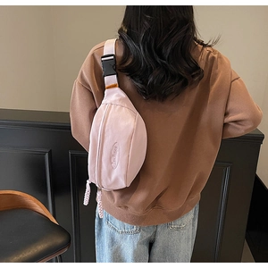 Detail of light purple nylon chest bag featuring adjustable strap and woven zipper puller