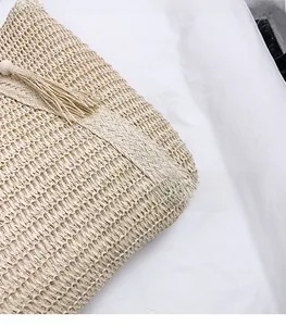 Close-up of beige woven straw tote bag texture with decorative fiber tassel detail