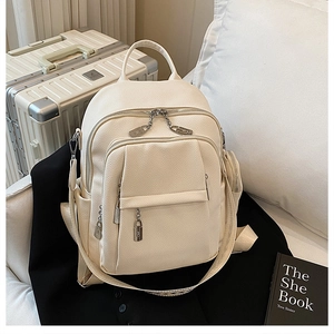 Detail of premium cream-white faux leather backpack with metallic zippers and lychee texture