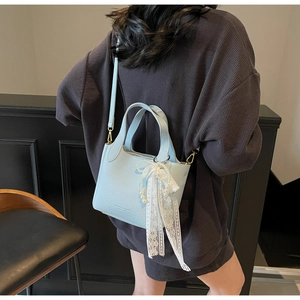 Detail of light blue pebble leather bucket bag with lace bow and pearl charm ornament