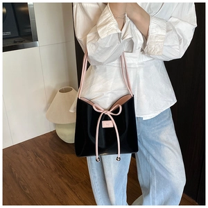 Détail du sac seau noir et rose avec cordon à nœud et fine bandoulière élégante