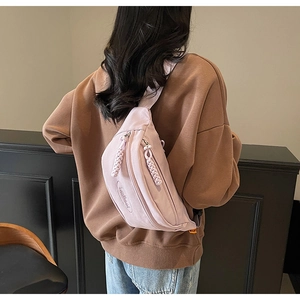 Detailed view of light purple canvas crossbody chest bag with double zipper and round logo