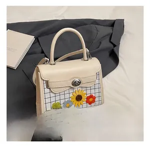 Close-up of beige leather bag with sunflower embroidery and metal twist lock
