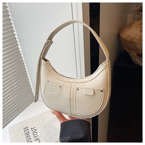 Close-up of beige lychee textured crescent bag with silver rivet pocket details