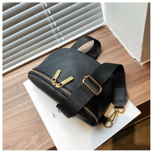 Detail of black litchi grain leather bag with gold dual-zipper and adjustable strap