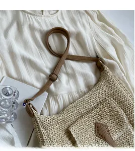 Detail of adjustable brown leather strap and woven texture on beige straw shoulder bag