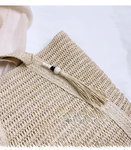 Detail of woven straw tote bag with beaded tassels and intricate textured patterns