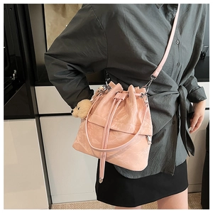 Pink drawstring bucket bag with pleated texture and bear charm shown on a model