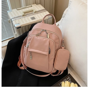 Detail of pink pebbled leather backpack with metal zipper locks and matching mini pouch