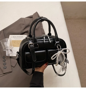 Detail of vintage black Boston bag with pearl bow charm and decorative lace ribbons
