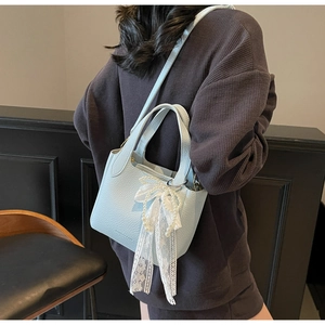 Detail of light blue lychee pattern handbag with lace pearl bow and shoulder strap