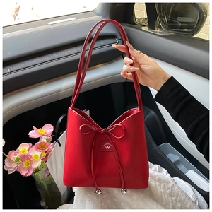Détail du sac à bandoulière en cuir rouge avec nœud en cuir fin et perles en métal argenté