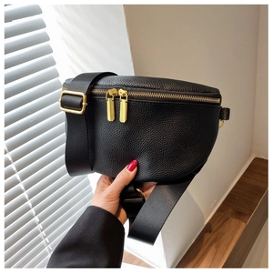Close-up of black lychee grain leather crossbody bag with golden dual zippers and strap