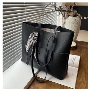 Close-up of black lychee grain leather tote bag with exterior pocket and chic scarf detail
