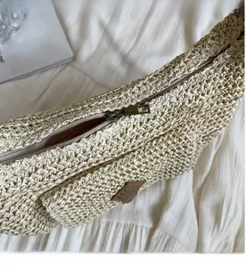 Detail of smooth metal zipper and woven texture on this beige straw beach bag