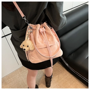Detail view of pink glossy drawstring bucket bag with cute plush puppy charm accessory