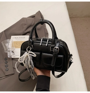 Detail of black Boston bag with pearl charm and checkered bow in urban lifestyle setting