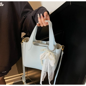 Detail of light blue lychee texture handbag with white lace pearl bow and gold hardware