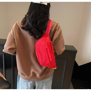 Close-up of red canvas waist bag with embossed logo and braided zipper pulls