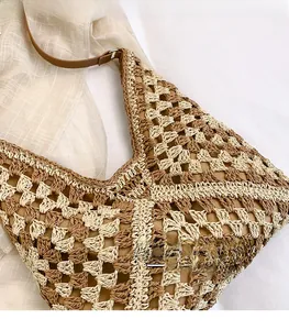 Detail of hollow diamond crochet texture and brown leather strap on straw tote bag