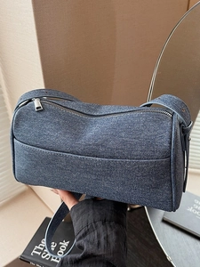 Classic dark blue denim shoulder bag with silver zipper in a modern lifestyle setting