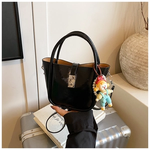 Detail of black patent leather bucket bag with glossy finish and cute cartoon charm