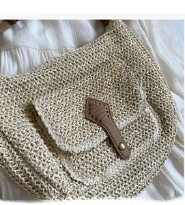 Close-up of the natural woven straw texture and faux leather strap on a beach crossbody bag