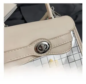 Detail of silver twist lock on beige handbag with floral embroidery and mesh texture