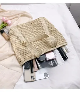Detailed view of spacious woven straw tote bag filled with iPad, phone, and cosmetics
