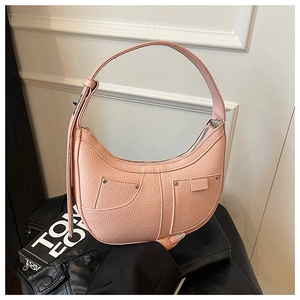 Macro detail of pink lychee leather dumpling bag with silver rivets and stitching