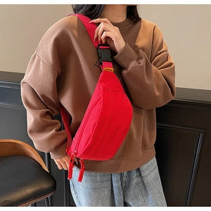 Close-up of a vibrant red canvas chest bag worn by a model with adjustable strap details