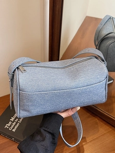 Light blue denim cylinder shoulder bag with silver zipper and adjustable strap